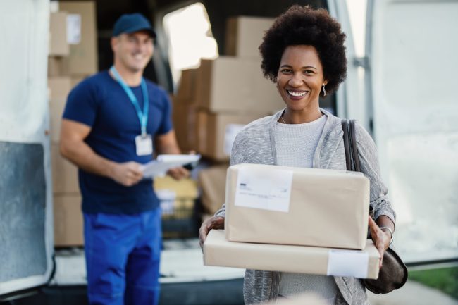 Happy African American woman holding her delivered packages.